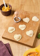 Cooking pumpkin ravioli, heart-shaped ravioli cut out on a wooden board. Pumpkin recipes.