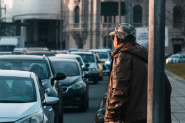 old man looking at the traffic that is generated on the avenue