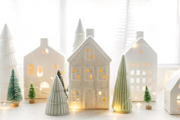 Christmas little ceramic houses, white snowy trees and golden lights on window. Xmas background....