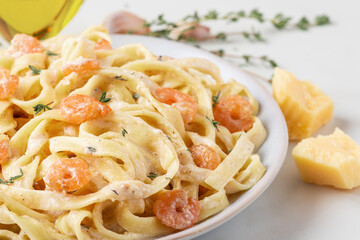 Close up of creamy shrimp Alfredo fettuccine pasta garnished with fresh thyme, parmesan cheese, garlic, olive oil, and sprinkle of peppercorns. Italian food