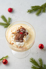 A glass of white pudding with a gingerbread man on top