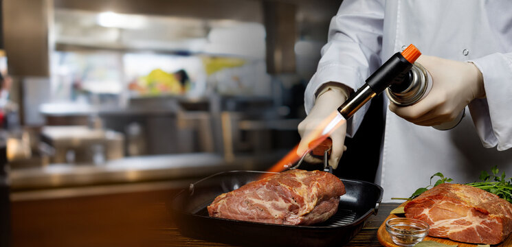 A chef uses a torch to process meat.