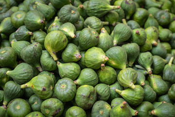 A pile of unripe, green fig fruits  (Ficus carica). bazaar market.