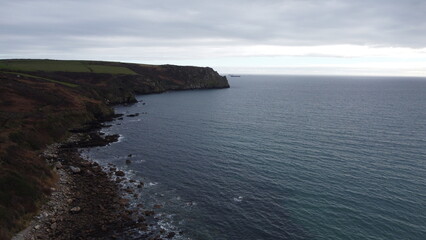 Obraz premium Rocky coastline with cliffs and ocean under cloudy sky