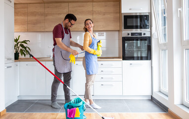 Young couple preparing for chores in kitchen