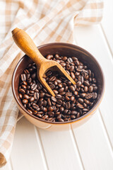 Roasted coffee beans in bowl on white table.