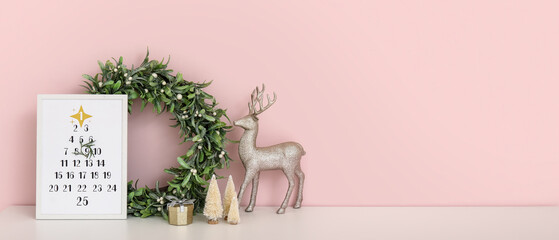 Christmas calendar with wreath and decor on drawers near pink wall