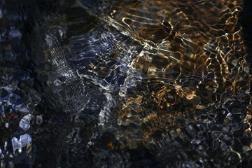 Clean water surface in a mountain stream river. Abstract of water surface in slow motion and pebbles at the bottom