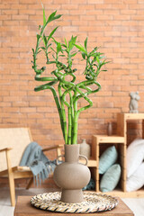 Vase with green bamboo branches on table in room