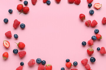 Frame made of fresh raspberries, blueberries and strawberries on pink background