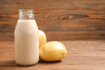 Bottle of tasty potato milk on wooden background