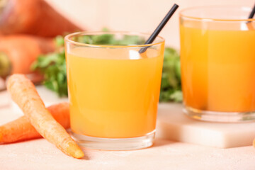Glasses of fresh carrot juice on pink table