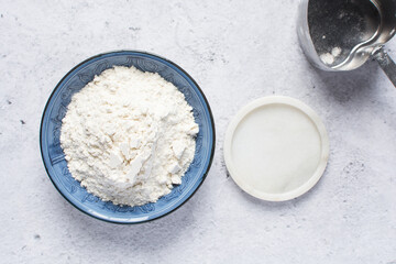 Overhead view of All purpose flour in a blue plate, baking flour in a plate on a marble countertop