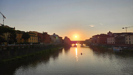 Naklejka premium sunset over Ponte Vecchio captures the majestic architecture along the banks of the Arno River in Florence, Italy.