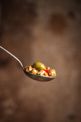 Close-up of Green Olives with Garlic and chili on a Spoon, olive oil drizzling on olives Rustic