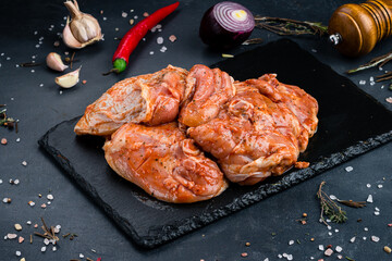Marinated barbecue chicken with spices and salt on a dark background.