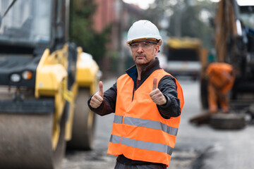 Construction worker giving thumbs up on a busy road site during daylight in an urban setting