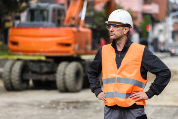 Construction worker in safety gear supervises project at urban site on a sunny day