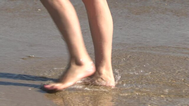 gros plan sur des pieds de femme marchant sur le bord de mer