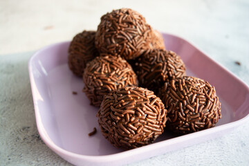 Close-up of chocolate brigadeiros on a pink plate.