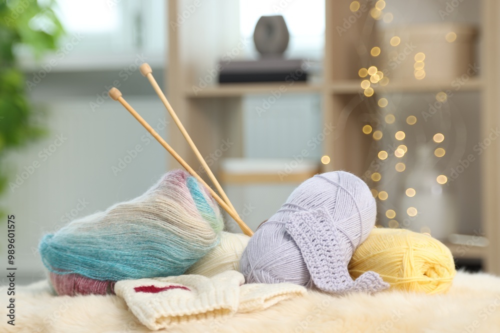 Sticker Skeins of yarn, needles and knitting sample on soft surface indoors