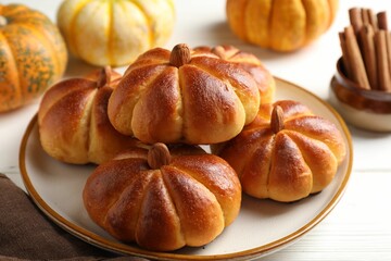 Tasty pumpkin shaped buns and ingredients on white wooden table, closeup