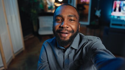 Obraz premium Smiling influencer using mobile phone to do live broadcast for subscribers, showing his home studio. Internet star films himself for viewership using POV camera, engaging with fans watching
