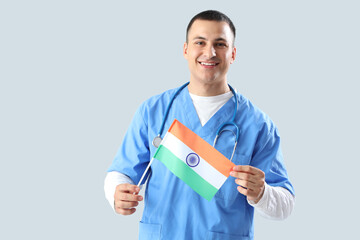 Male doctor with flag of India on grey background. National Doctor's Day celebration