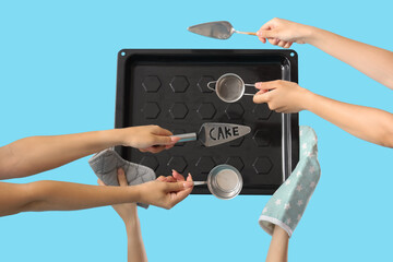 Female hands with different baking utensils on blue background