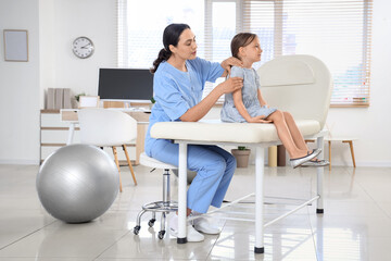 Female osteopath working with little patient in clinic