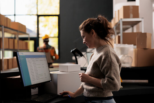 Stockroom supervisor analyzing merchandise checklist on computer, working at products inventory report in warehouse. Storage room supervisor standing at counter desk checking goods logistics