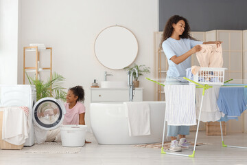 African-American woman and her daughter doing laundry in bathroom
