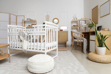 Interior of bedroom with baby crib, shelf units and workplace