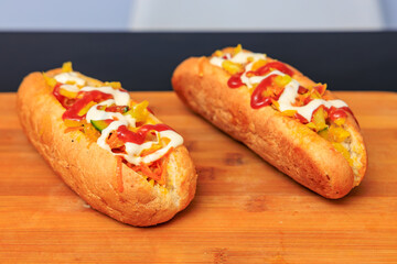 Two hot dogs with ketchup and mustard on a wooden table