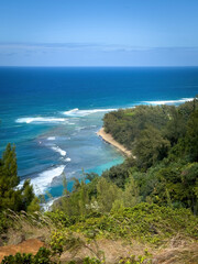 Fototapeta premium Kee Beach on the Hawaiian island of Kauai seen from Kalalau Trail against blue sky with clouds
