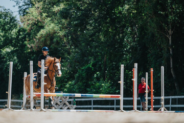Young equestrian rider skillfully guides horse over a jumping obstacle during practice at an...