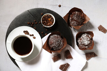 Black board with sweet chocolate muffins and cup of coffee on white background