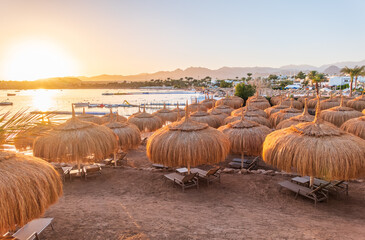 Straw umbrellas on empty beach. Beautiful empty beach with sun umbrellas and sunbeds