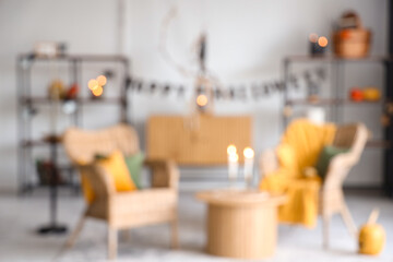 Blurred view of living room decorated for Halloween with armchairs, table and shelf units