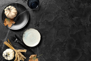 Beautiful table setting with fresh pumpkins, wheat, spiders and autumn leaves for Halloween celebration on black background