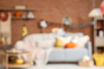 Blurred view of festive living room with grey sofa, pumpkins and Halloween decorations