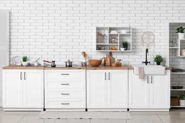 Interior of light kitchen with different dishes on counters and shelves
