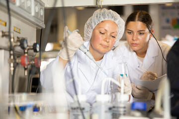 Woman scientist and her assistant conduct scientific experiments in a chemical laboratory