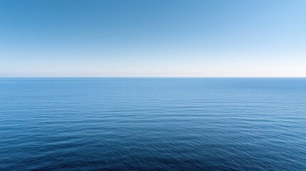 A serene view of a calm ocean under a clear blue sky, evoking tranquility and peace.