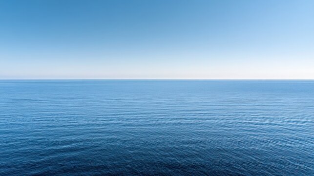 A serene view of a calm ocean under a clear blue sky, evoking tranquility and peace.