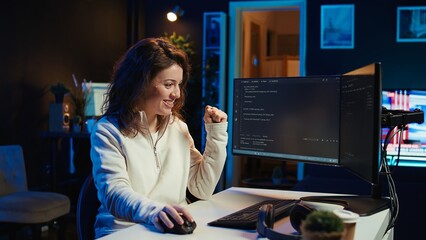 Joyous woman doing software quality assurance celebrating after reading source code and finding no errors. Cheerful engineer excited after inspecting coding on desktop PC, seeing no issues, camera B