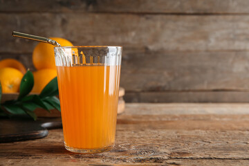 Glass of fresh orange juice and fruits on wooden background