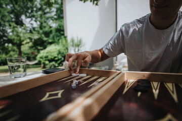 A young man enjoys a game of backgammon outdoors in a serene garden setting, capturing leisure and relaxation.