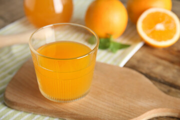Glass of fresh orange juice and fruits on wooden background
