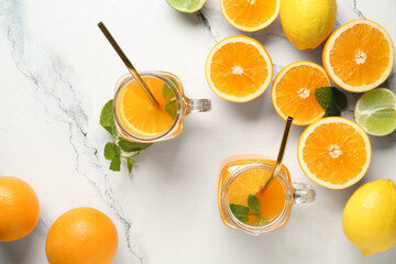 Mason jars of fresh orange juice with mint and different citrus fruits on white background